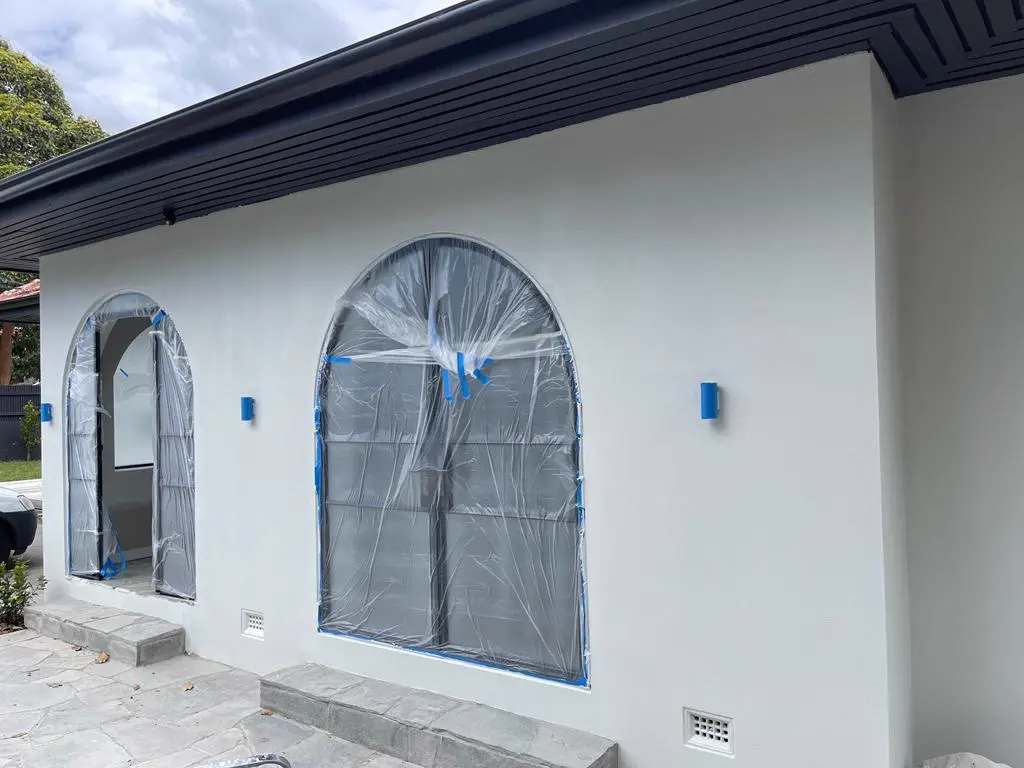 Arched windows masked and prepared for exterior painting on a rendered Melbourne home