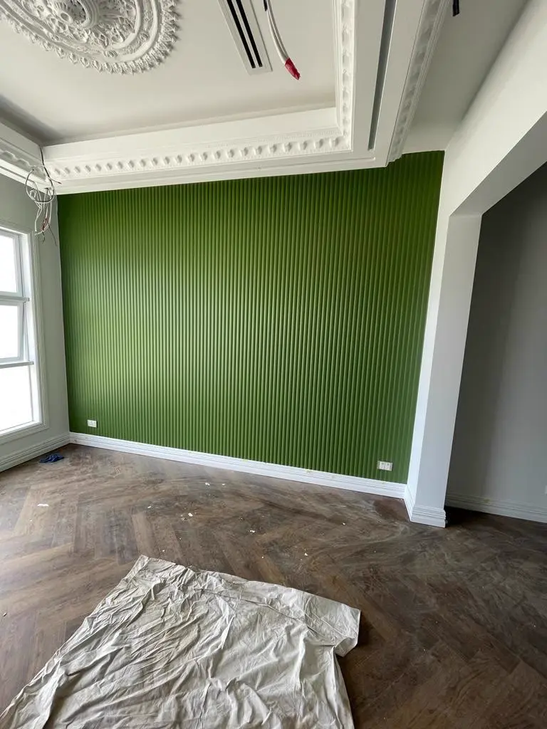 Deep green feature wall painted in a heritage Melbourne living room with ornate cornices