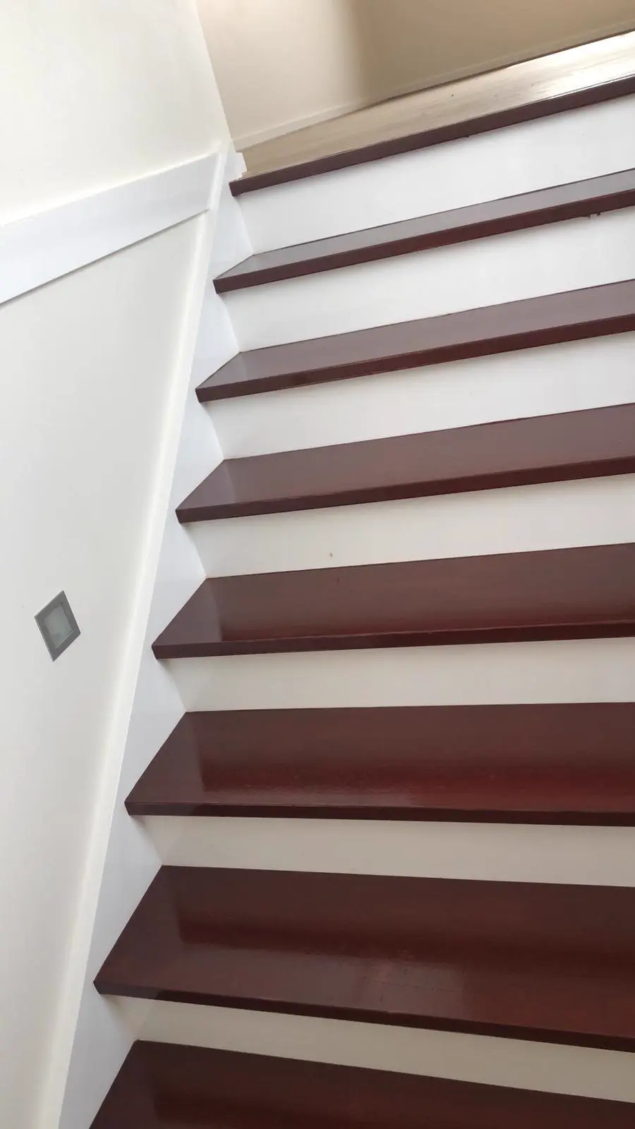 Stained red timber stair treads against crisp white risers