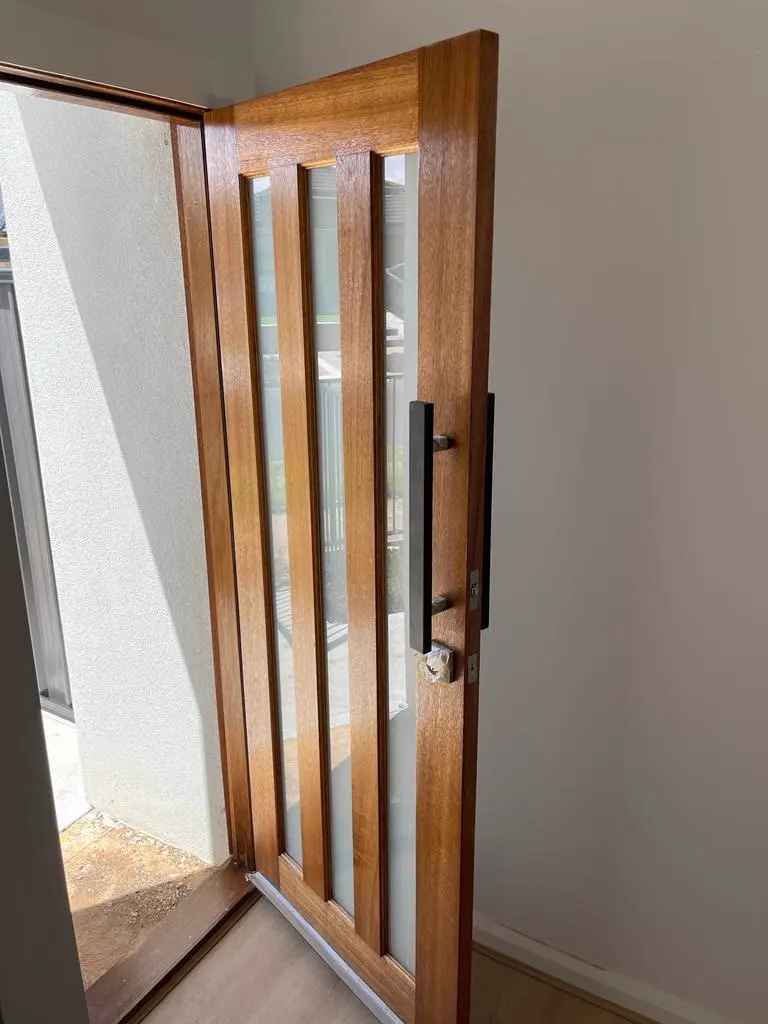 Stained timber pivot entry door with clear coat finish by Freshy Painting